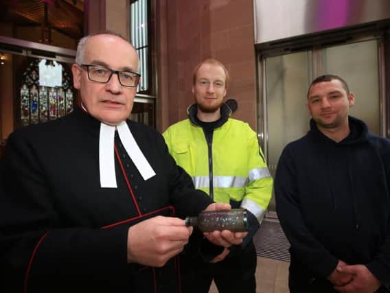 Reverend Canon Keith Farrow with workmen Adam Green and Rob Bowyer with the discovered bottle.