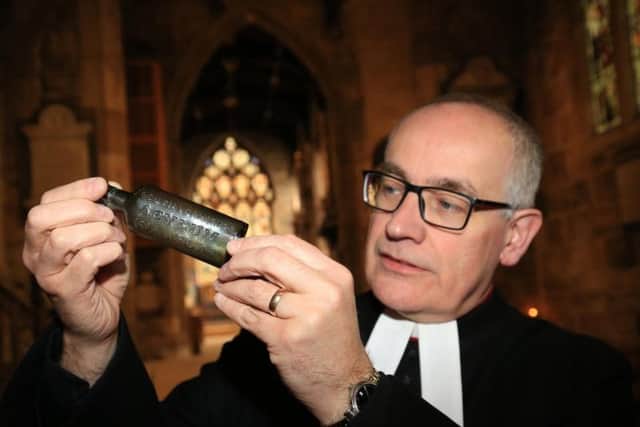Reverend Canon Keith Farrow with the bottle found in the church roof.