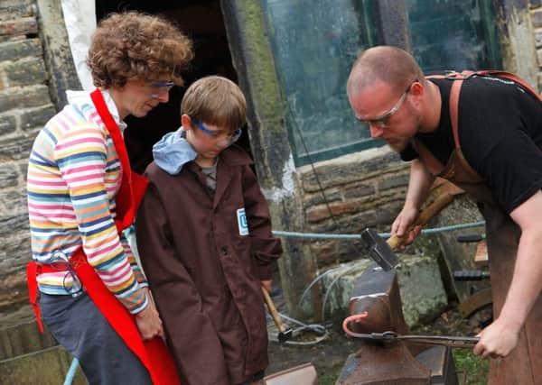 A family have a go at traditional skills at the blacksmith forge at Abbeydale Industrial Hamlet