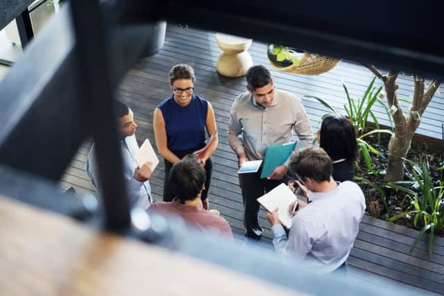 High angle view of business people discussing at lobby. Male and female professionals are working in office. Focus is on executives at workplace.
