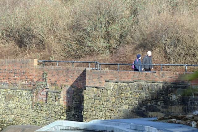 A couple walk beside the extended flood defence walls along the River Don
