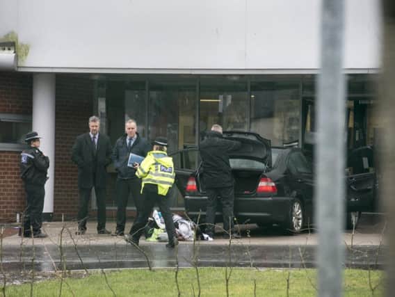 Police officers inspect a BMW car is left outside the damaged doors of Fir Vale School in Sheffield after the driver tried to ram his way into the building at the start of the school day.