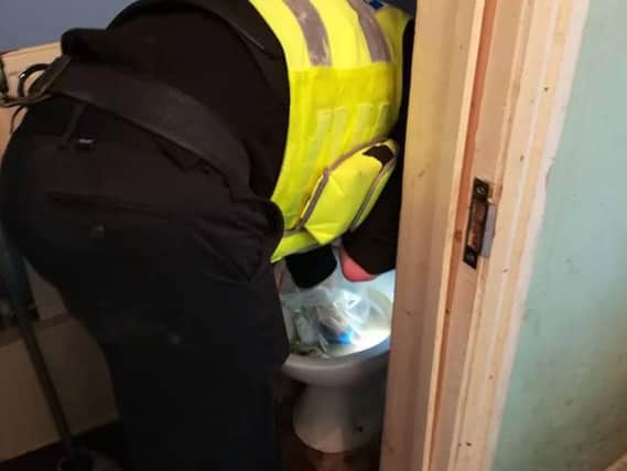 An officer searches a blocked toilet at the property