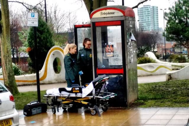 Paramedics attend to a man who is believed to have taken the drug spice inside a phone box at Devonshire Green