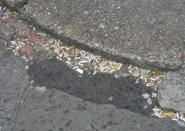 A pile of discarded cigarette ends in the gutter.