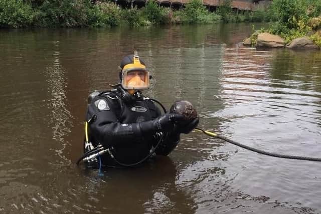 A police diver with the item that was thought to be a cannonball.