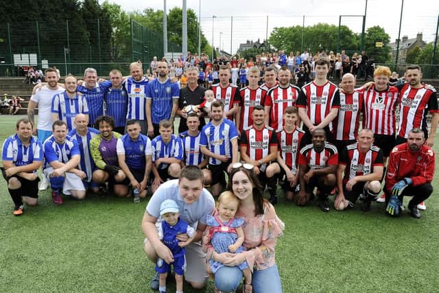 Lucas Brand with sister Isla, dad Luke and mum Danielle Eyre in front of the charity football teams made up of Sheffield Wednesday and Sheffield United fans